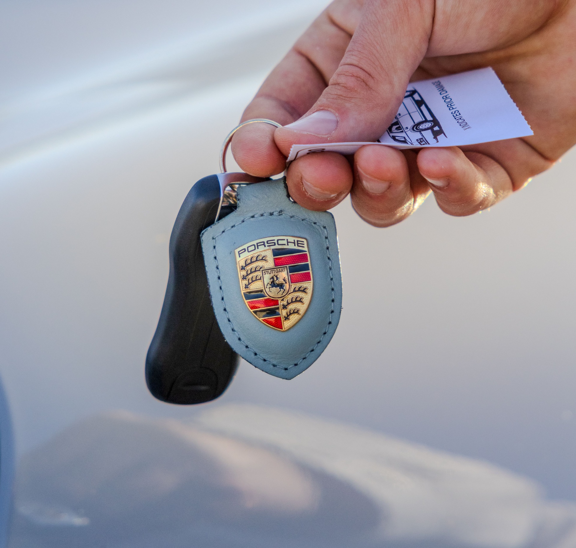 Close-up of a Porsche key and claim ticket in the attendant's hand